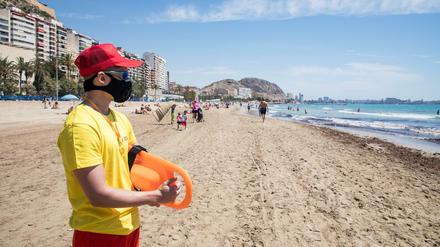 Ein Rettungsschwimmer mit Mundschutz am Strand von Alicante in Spanien.