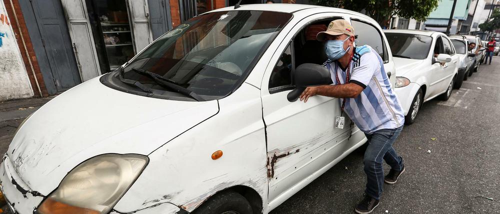 Ein Mann in Venezuela schiebt sein Auto zu einer Tankstelle.