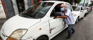 Ein Mann in Venezuela schiebt sein Auto zu einer Tankstelle.