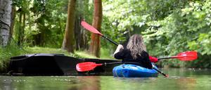 Touristen fahren in einem Paddelboot über ein Spreewald-Fließ im Hochwald in Burg Kauper (Brandenburg).