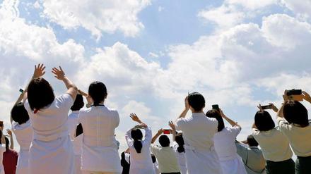 Medizinisches Personal des Zentralkrankenhauses der Selbstverteidigungskräfte stehen und winken, während die Kunstflugstaffel der japanischen Selbstverteidigungsstreitkräfte am Himmel über Tokio fliegt.