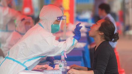 China, Wuhan: Ein Mitarbeiter des Gesundheitswesen entnimmt eine Rachenprobe für einen Corona-Test bei einer jungen Frau in einer Grundschule im Bezirk Dongxihu.