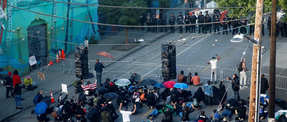 Demonstranten knien vor einer Polizeiabsperrung in Seattle auf dem Boden. 