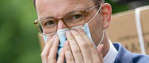 Jens Spahn (CDU), Bundesgesundheitsminister, setzt sich bei der Übergabe der ersten Lieferung von 100 Millionen gespendeten Schutzmasken eine Maske auf.