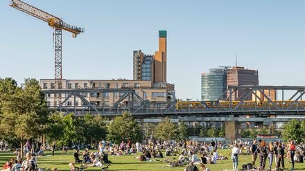 Blick auf den gut besuchten Gleisdreieckpark mit U-Bahn-Trasse und Potsdamer Platz im Hintergrund.