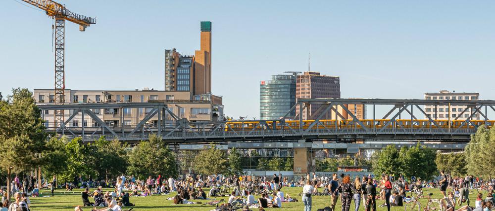 Blick auf den gut besuchten Gleisdreieckpark mit U-Bahn-Trasse und Potsdamer Platz im Hintergrund.