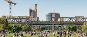 Blick auf den gut besuchten Gleisdreieckpark mit U-Bahn-Trasse und Potsdamer Platz im Hintergrund.