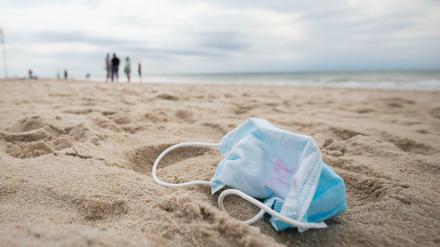 Ein gebrauchter Mundschutz mit Resten von Lippenstift liegt am Strand vor der Strandpromenade von Westerland auf Sylt.