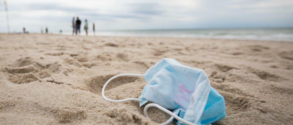Ein gebrauchter Mundschutz mit Resten von Lippenstift liegt am Strand vor der Strandpromenade von Westerland auf Sylt.