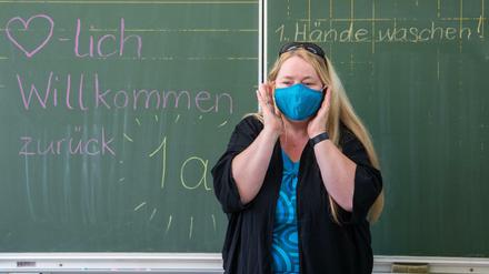Die Lehrerin einer ersten Grundschulklasse in Sachsen erklärt ihren Schülern, wie man eine Mund-Nasen-Schutzmaske richtig anlegt und trägt.