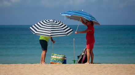 Ein Paar stellt Sonnenschirme am Strand von Palma de Mallorca auf.