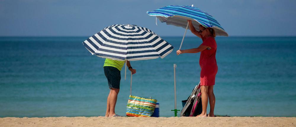 Ein Paar stellt Sonnenschirme am Strand von Palma de Mallorca auf. 