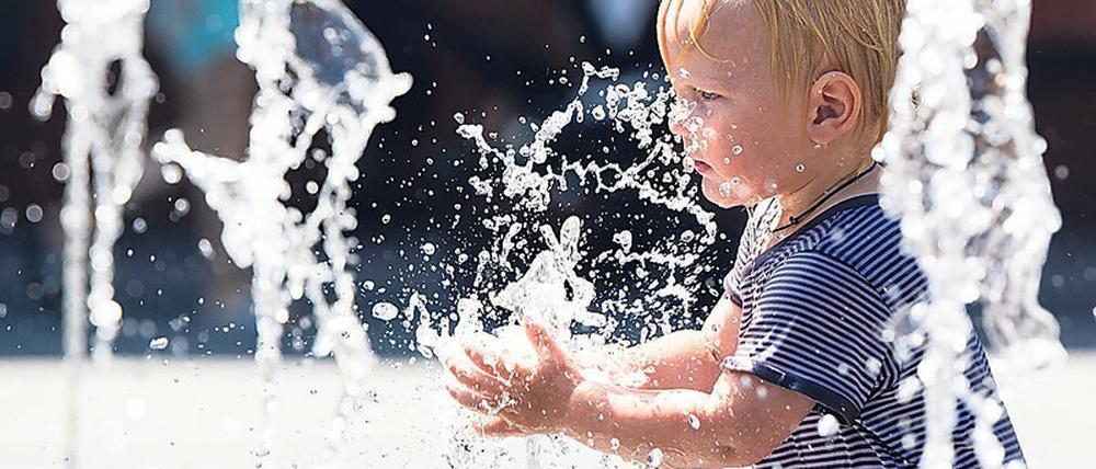 Ein Zweijähriger planscht im Juli 2019 bei Temperaturen nahe 40 Grad Celsius in einem städtischenBrunnen. In Innenstädten machen sich Hitzewellen und Rekordtemperaturen besonders stark bemerkbar.