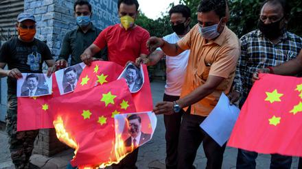 Indische Anti-China-Aktivisten zünden eine chinesische Flagge und Fotos des KP-Chefs Xi Jinping an.