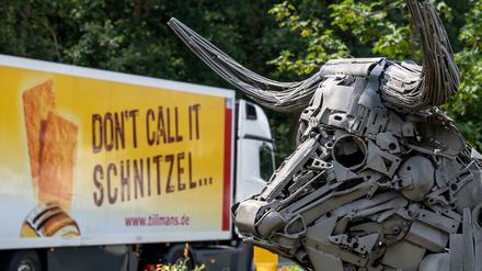 Ein LKW der Tönnies-Tochterfirma Tillmanns mit der Aufschrift "Don·t call it Schnitze" fährt an einer Plastik vorbei, die einen Bullen darstellt. 