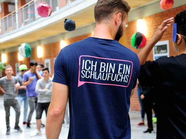 Jugendliche Geflüchtete spielen und kommunizieren mit einem Erzieher im Lichthof eines Gebäudes.