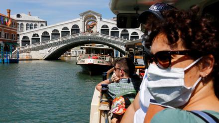 Touristen passieren mit dem Wassertaxi in Venedig die Rialto-Brücke.