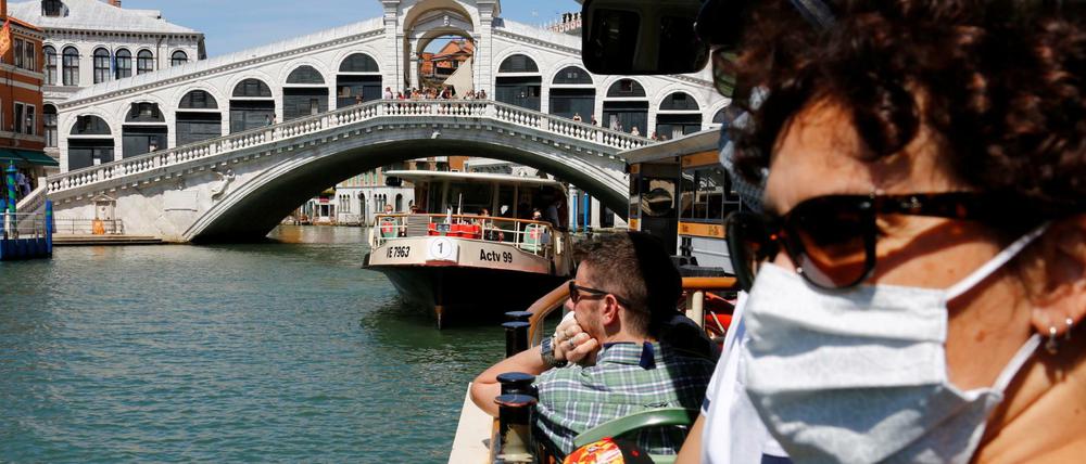 Touristen passieren mit dem Wassertaxi in Venedig die Rialto-Brücke.