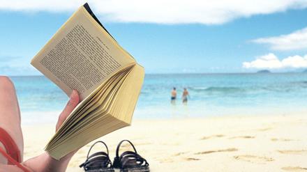 Frau liest Buch am Strand.