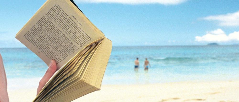 Frau liest Buch am Strand.