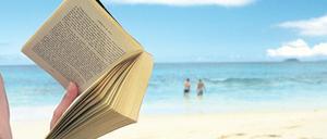 Frau liest Buch am Strand.