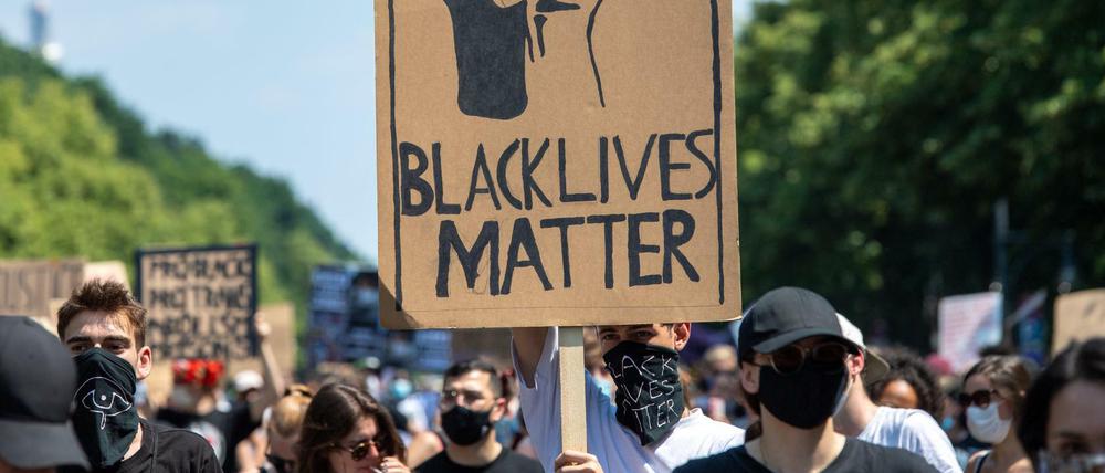 Bei der „Black Lives Matter"- Demonstration an der Siegessäule hält ein Teilnehmer ein Plakat.