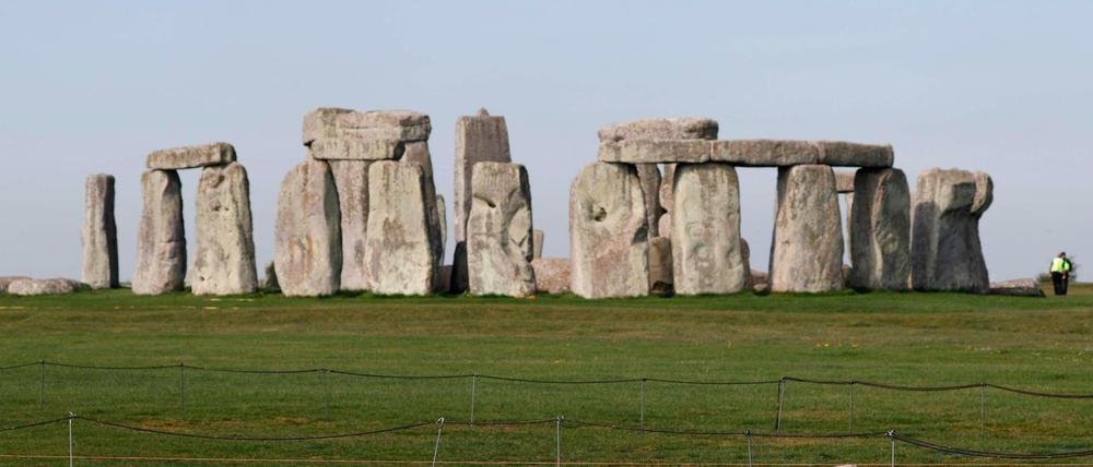 Vor dem Steinzeitmonument Stonehenge laufen Schafe über eine Weide.