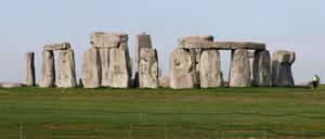Vor dem Steinzeitmonument Stonehenge laufen Schafe über eine Weide.