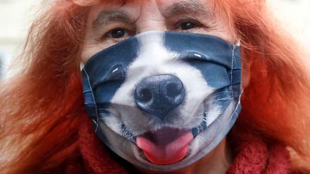 Eine Frau in den USA trägt während eines Spaziergangs eine Stoffmaske, auf der ein Bild einer Hundeschnauze gedruckt ist.
