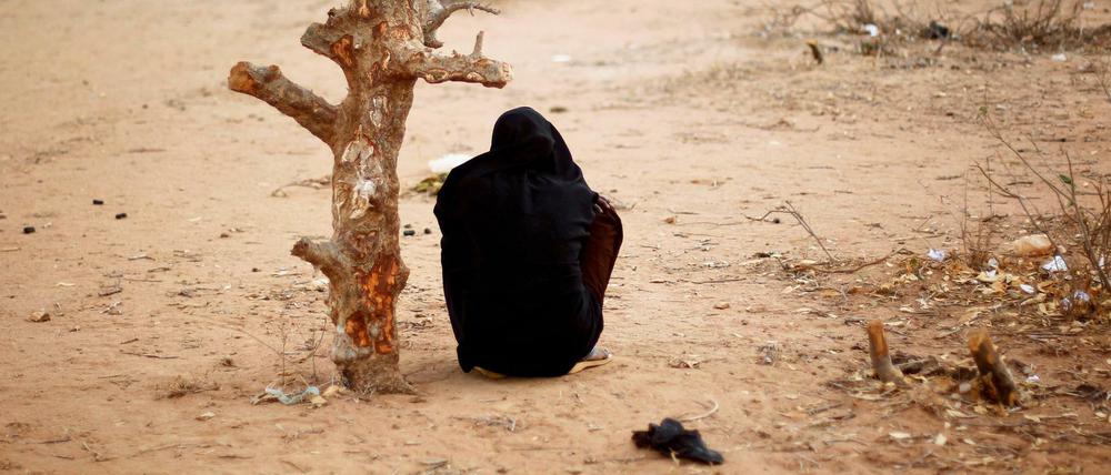 Eine schwangere Frau aus Somalia sitzt in Kenia an einem verdorrten Baum.