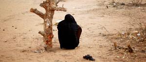 Eine schwangere Frau aus Somalia sitzt in Kenia an einem verdorrten Baum.