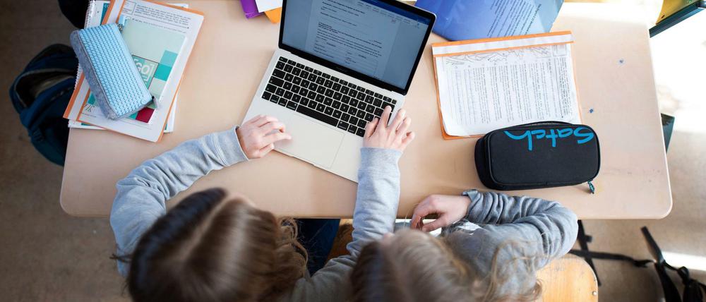 Zwei Schülerinnen arbeiten im Klassenraum gemeinsam an einem Laptop.