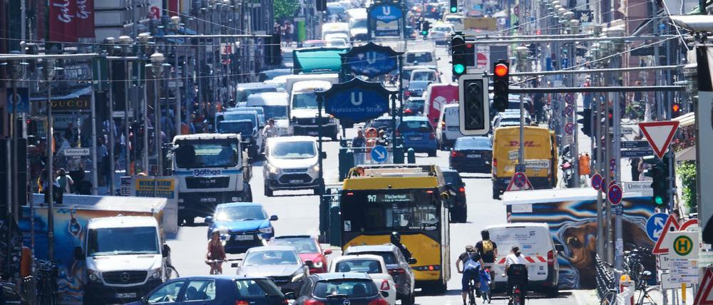 Autos, Busse, Lastwagen, Radfahrer und Fußgänger teilen sich die Friedrichstraße am Checkpoint Charlie zur Mittagszeit.