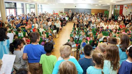 Zweitklässler singen in einer Schulaula für neu Eingeschulte und ihre Eltern.