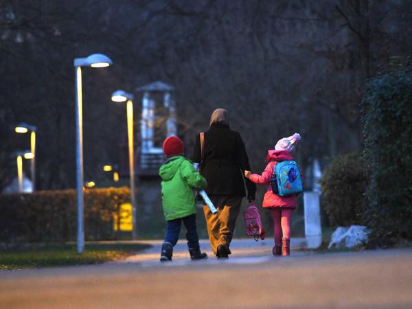 Eine Frau, die Kopftuch trägt, holt in am späten Nachmittag ihre Kinder von der Schule ab.