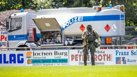 Ein Beamter eines Sondereinsatzkommandos SEK geht über einen Sportplatz nahe der Gemeinde Oppenau, welcher der Polizei als Sammelpunkt dient. 