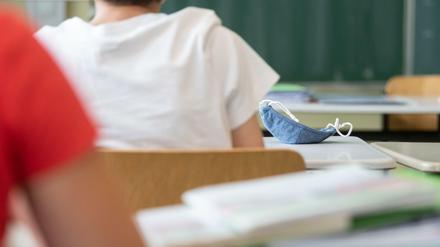 Eine Mund-Nasen-Bedeckung liegt während einer Unterrichtsstunde auf einem Schultisch.