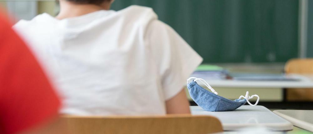 Eine Mund-Nasen-Bedeckung liegt während einer Unterrichtsstunde auf einem Schultisch.