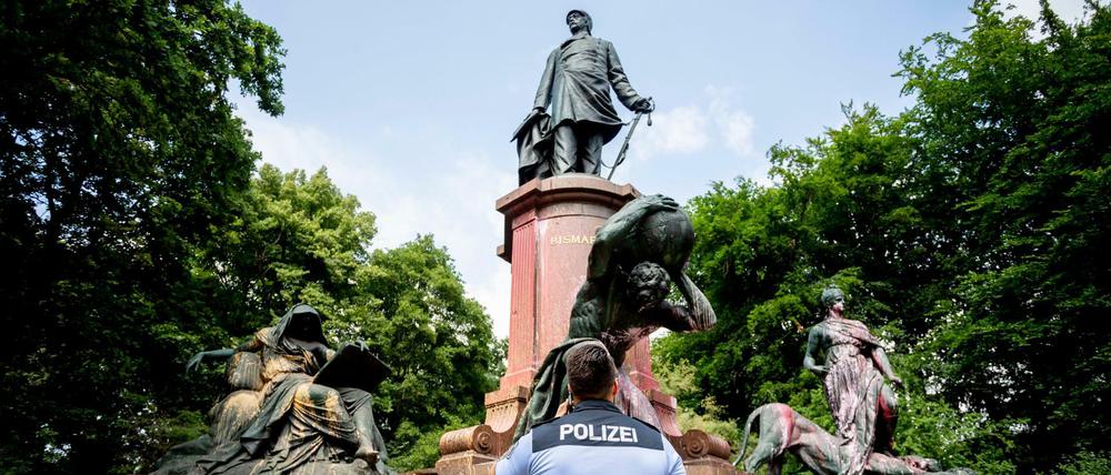 Ein Polizist steht vor dem mit Farbe beschmierten Bismarck-Nationaldenkmal in Berlin, wobei ebenfalls der Schriftzug "Decolonize Berlin" aufgesprüht wurde.