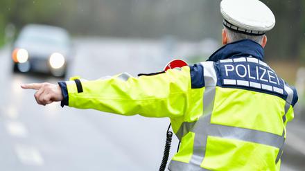 Ein Polizist hält bei einer Geschwindigkeitskontrolle Fahrzeuge an.