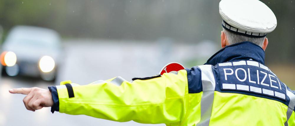 Ein Polizist hält bei einer Geschwindigkeitskontrolle Fahrzeuge an.
