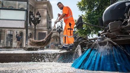 Mitarbeiter der Stadtreinigung beseitigen am Morgen vor der Alten Oper Scherben der zertrümmerten Scheiben einer Bushaltestelle. 