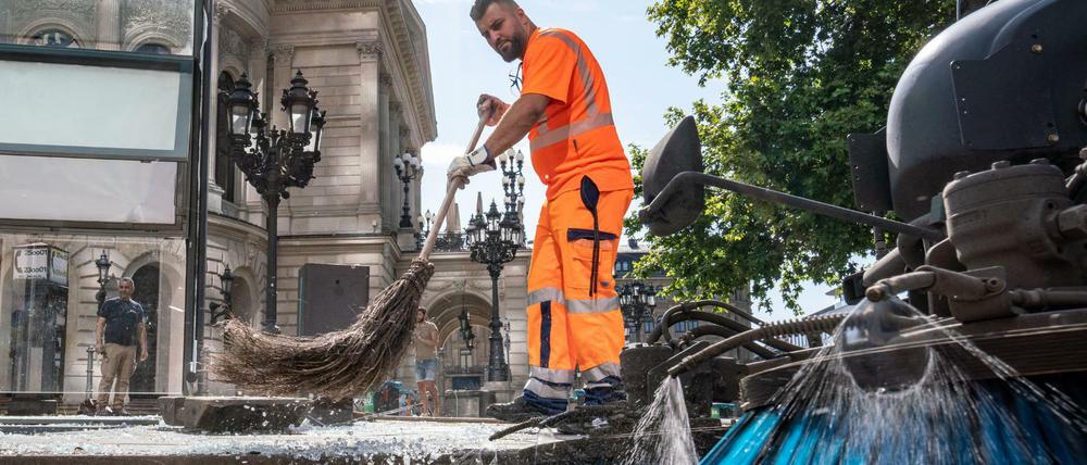 Mitarbeiter der Stadtreinigung beseitigen am Morgen vor der Alten Oper Scherben der zertrümmerten Scheiben einer Bushaltestelle. 