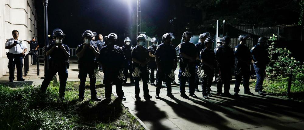 Polizisten beobachten Demonstranten, die sich in einem Protestcamp vor dem Rathaus versammeln am 20. Juni 2020.