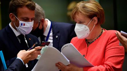 Emmanuel Macron (l), Präsident von Frankreich, fotografiert mit seinem Smartphone Unterlagen ab die Bundeskanzlerin Angela Merkel (CDU) ihm vor einem Treffen am runden Tisch im Rahmen des EU-Gipfels zeigt.