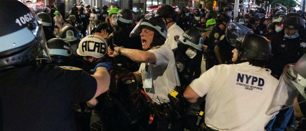 Ein Beamter der New Yorker Polizei schlägt mit einem Knüppel nach einem Demonstranten.