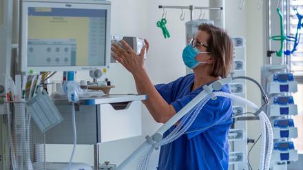 Eine Krankenschwerster prüft ein Beatmungsgerät in einem Zimmer einer Intensivstation.