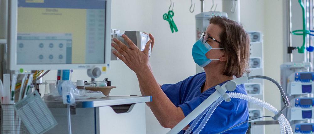 Eine Krankenschwerster prüft ein Beatmungsgerät in einem Zimmer einer Intensivstation.