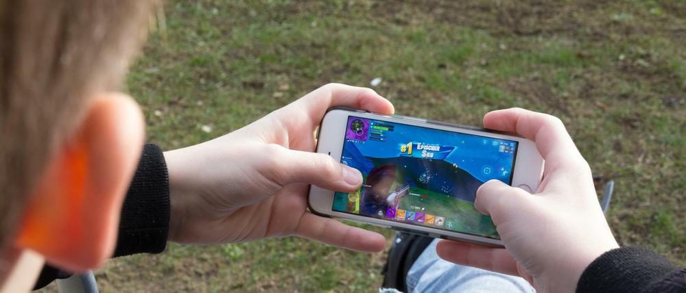 Ein Junge spielt auf einem Smartphone. Immerhin sitzt er dabei an der frischen Luft.