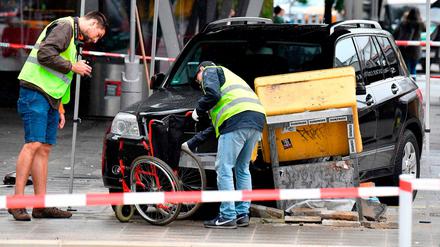 Ermittler untersuchen einen Rollstuhl. Der Geländewagen fuhr auch gegen den Briefkasten rechts und kam dort zum Stehen.